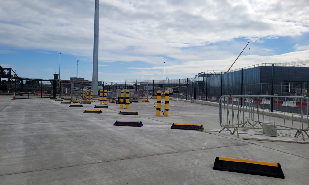 Large yard with black and yellow wheel stops and bollards. It looks industrial.